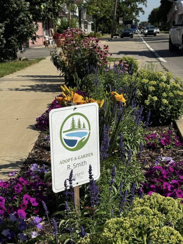 Colorful roadside garden with adoption sign