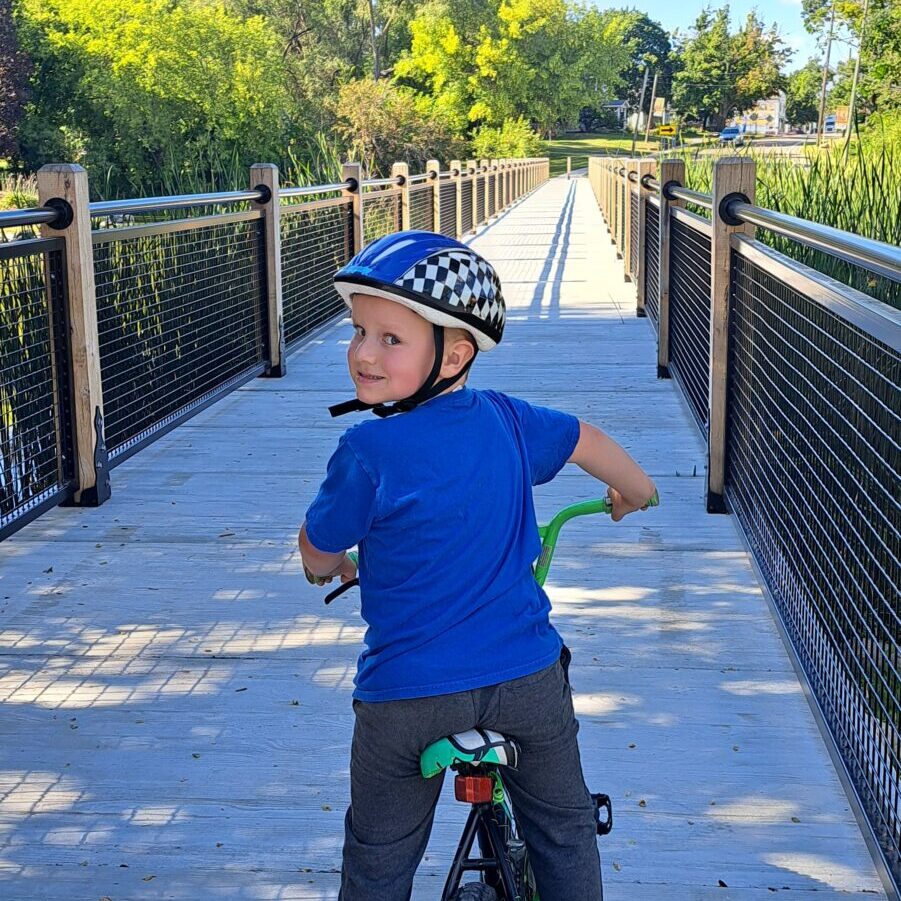 Child biking on bridge in sunny park