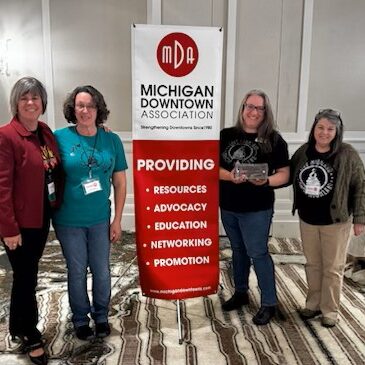 Group standing by Michigan Downtown Association banner.
